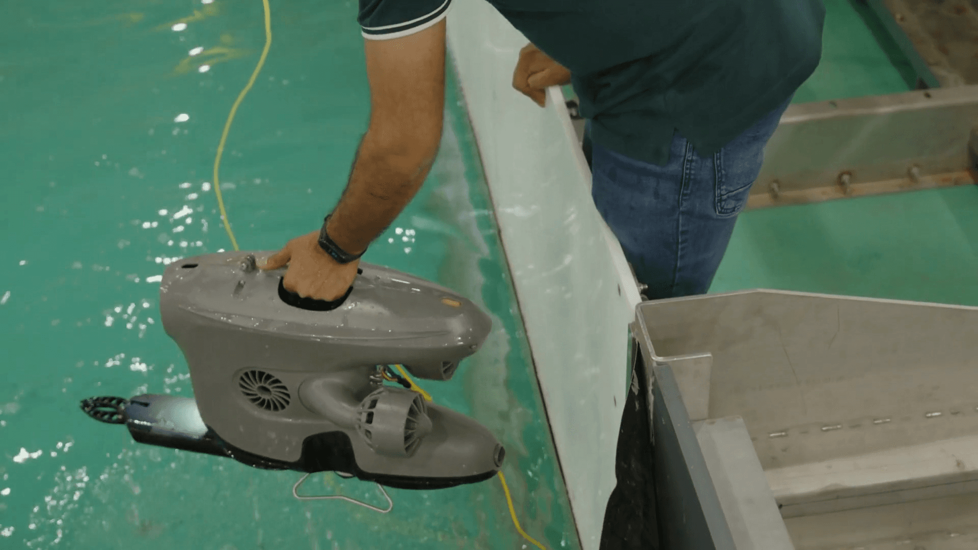 Researcher preparing an underwater robot for a pool test